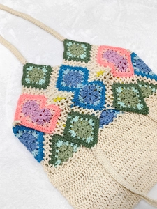 Close-up detail of a handmade crochet granny square tote bag with colorful floral patterns
