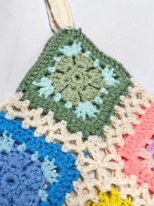 Detailed close-up showing the handmade crochet texture and colorful granny square stitching