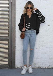 Detail of a black oversized striped polo sweater paired with ripped jeans and a brown bag