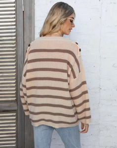 Close-up of decorative buttons and contrast striped knit texture on a loose sweater