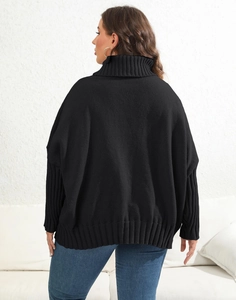 Detail of the oversized black turtleneck sweater featuring ribbed hem and dropped shoulders