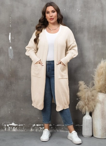 Détail d'un long gilet en maille beige avec de grandes poches et des poignets côtelés