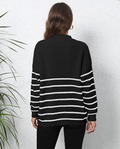 Rear view of loose black knit sweater featuring white striped sleeves and casual fit