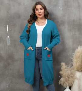 Detail of teal knit cardigan featuring deep pockets with a red heart embroidery patch