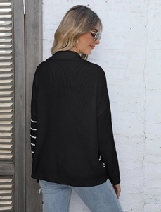 Detail of black knit cardigan featuring white wavy stripes on sleeves and dropped shoulder
