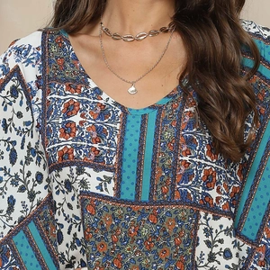 Detail of V-neck bohemian print top with layered gold shell necklaces and floral patterns