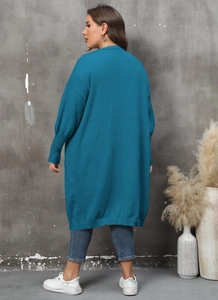 Détail d'un long gilet en maille bleu paon avec poignets côtelés et maille texturée