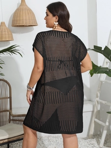 Back view of a black crochet beach cover-up with openwork mesh and wide sleeves