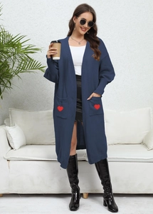 Detail of navy knit cardigan featuring red heart patch on pockets and long sleeves