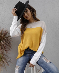 Detail of color block knit sweater in yellow and white styled with a black hat