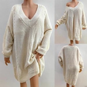 Detail of loose beige knit dress showing deep V-neckline and textured chunky fabric