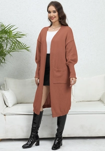 Close-up of rust red knit cardigan featuring oversized side pockets and lantern sleeves