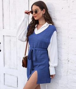Detail of blue knit vest dress with waist tie and V-neck styled over white shirt