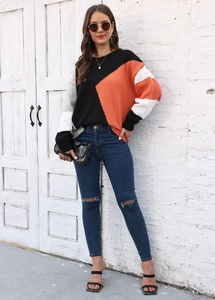 Dettaglio maglione in maglia color-block con motivi arancioni e grigi sulla modella