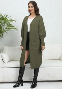 Olive green long knit cardigan featuring front pockets and ribbed cuffs in lifestyle setting