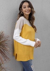 Detail of three-color patchwork knit sweater featuring side slit hem and round neck