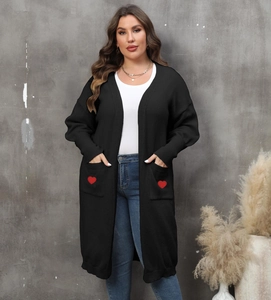 Detail of red heart embroidery on the front pocket of a black oversized cardigan