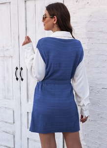 Detail of blue knit vest with waist belt layered over a white collared shirt for women
