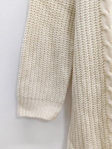 Detailed view of cream knit sweater featuring honeycomb texture and cable stitch patterns