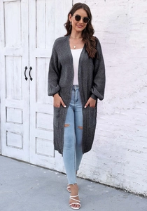 Texture dettagliata del lungo cardigan grigio scuro in maglia con ampie tasche laterali