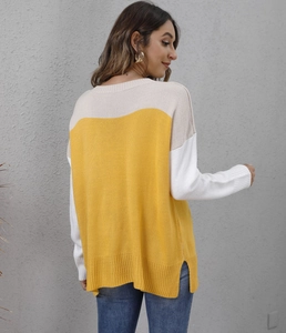 Detail of color-block knit sweater featuring side slit hem and cozy ribbed texture