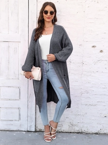 Dettaglio della maglia spessa del cardigan grigio scuro con ampie tasche e maniche a lanterna