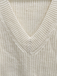 Close-up of premium ribbed knit texture and V-neckline on off-white woven dress