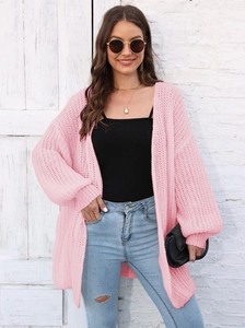 Detail of light pink knit cardigan showing hollow weave texture and lantern sleeves
