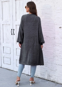 Dettaglio di un cardigan lungo grigio con maglia a grana grossa e maniche a palloncino