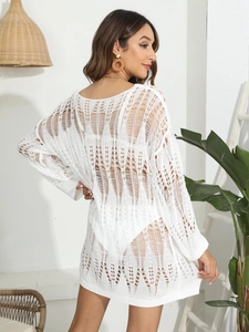 Detail of white crochet knit beach cover-up with hollow geometric patterns and long sleeves