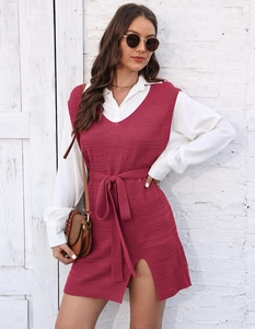 Detail of pink knit vest dress with side slit and waist belt over white shirt