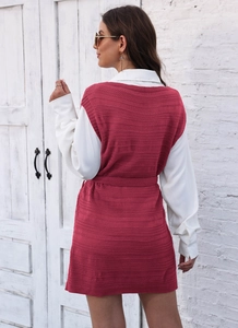 Detail of burgundy knit vest dress with chunky texture and waist belt on a white shirt