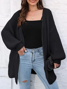 Close-up of black chunky knit texture and ribbed cuffs on loose-fit cardigan jacket
