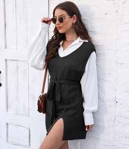 Detail of dark grey knit vest dress with side slit and matching belt over white shirt