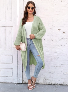 Dettaglio del cardigan in maglia verde chiaro con trama intrecciata e ampie tasche laterali