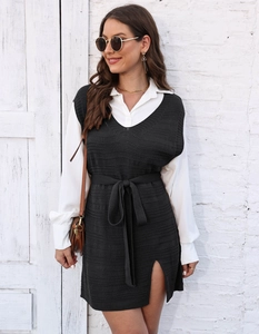Detail of dark grey knit vest dress with side slit and waist tie over white shirt