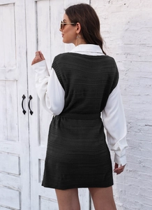 Detail of dark green knit long vest showing textured fabric and matching waist belt tie