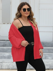 Detail of red pleated oversized cardigan with lantern sleeves and textured fabric