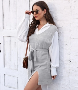 Detail of grey knitted vest dress with v-neck and drawstring waist over white shirt
