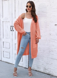 Dettaglio del cardigan lungo in maglia arancione brillante con grandi tasche e trama a costine
