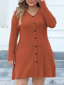 Détail de la robe en tricot rouge rouille avec décolleté en V et boutons noirs
