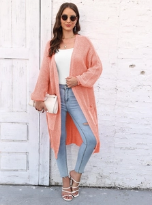 Dettaglio del cardigan in maglia corallo con maniche a lanterna e grandi tasche sul modello