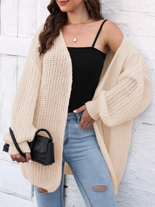 Detail of chunky knit texture and ribbed cuffs on a beige oversized cardigan sweater