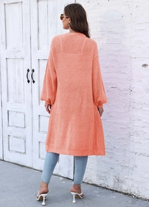 Vista posteriore di un lungo cardigan in maglia arancione con trama e maniche a lanterna