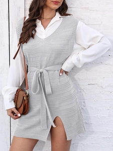 Detail view of a light grey knitted V-neck vest dress with a tied belt and side slits