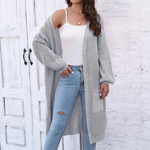 Dettaglio di un lungo cardigan grigio in maglia con tasche e maniche a lanterna