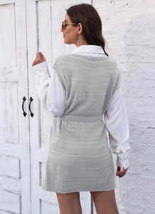 Detail of the gray knit vest dress featuring a textured wavy pattern and waist belt tie