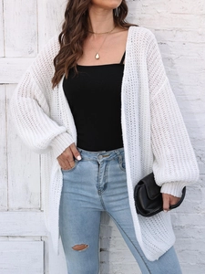 Close-up detail of white chunky knit cardigan with hollow textures and lantern sleeves