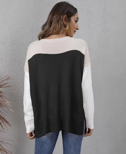 Detail of color-block knit sweater featuring split hem and textured tricolor stitching