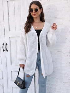 Detail of white chunky knit cardigan with lantern sleeves and textured stitch pattern